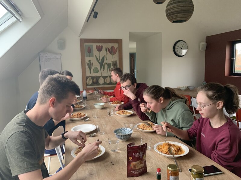 Studenten aan tafel eten spaghetti met verse bolognaisesaus